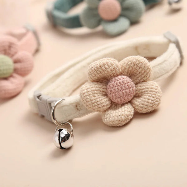 A beige knitted floral pet collar for cats and dogs with a pink center and silver hardware.