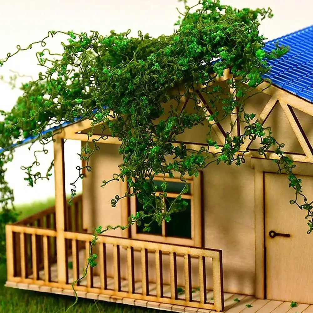 Holzminiaturhaus mit blauem Dach, bedeckt mit grünen Ranken und Pflanzen.