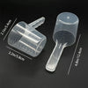 Transparent pet measuring spoon with scale for dog and cat food shown on a dark background.