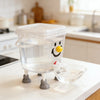 Distributeur d'eau automatique pour animaux en plastique transparent avec un visage souriant, sur un comptoir blanc.