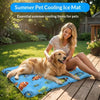 A smiling woman is sitting on a wooden deck with a golden retriever lying on a blue pet cooling ice mat filled with colorful 