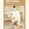 A white cat is interacting with an orange elastic ball and feathers on a carpet.
