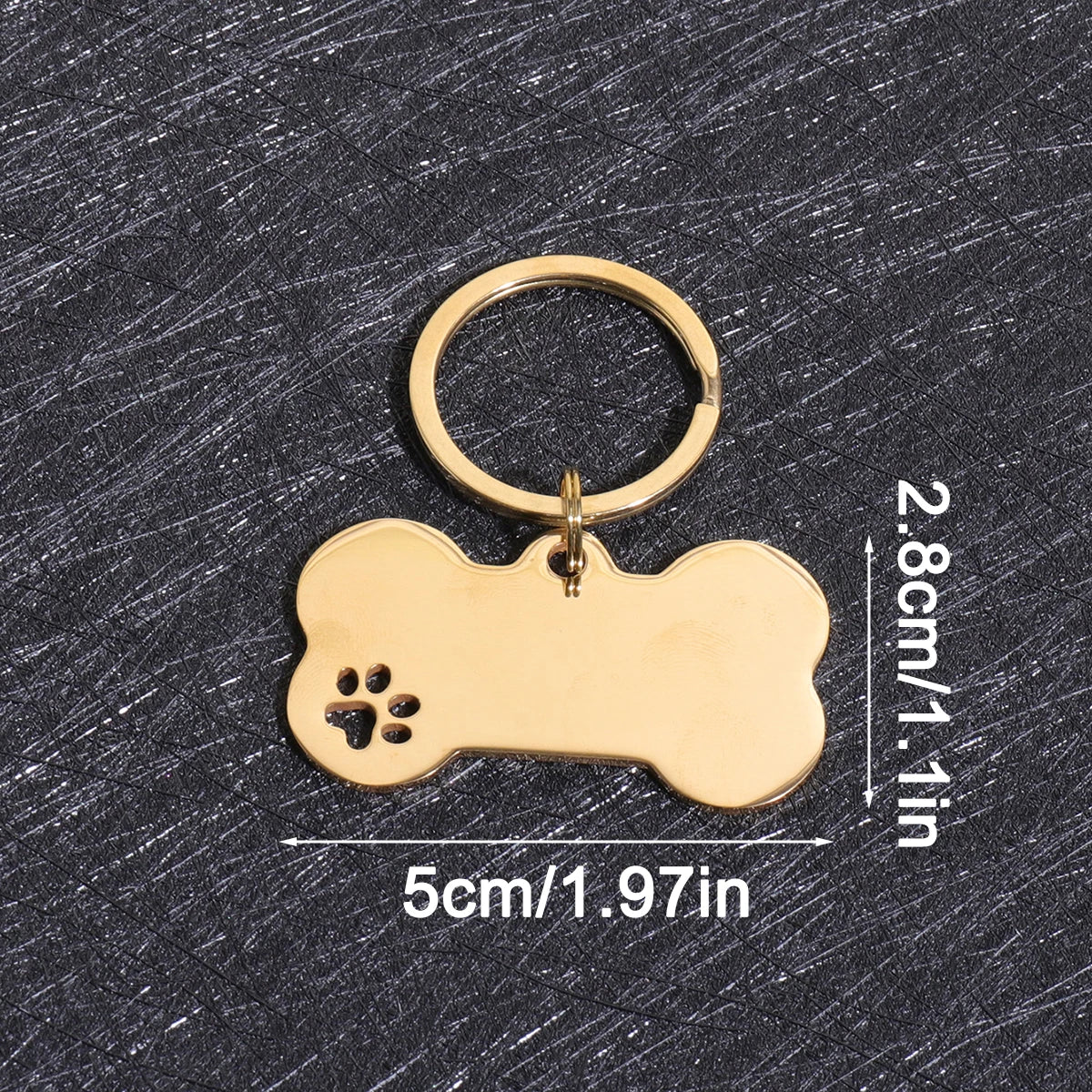 A gold-colored bone-shaped dog ID tag with a circular keyring, shown against a dark gray background.