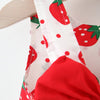 Nahaufnahme eines weißen Stoffes mit roter Erdbeer-Muster und einem weißen Riemchen, Teil eines Sommerkleid-Sets.