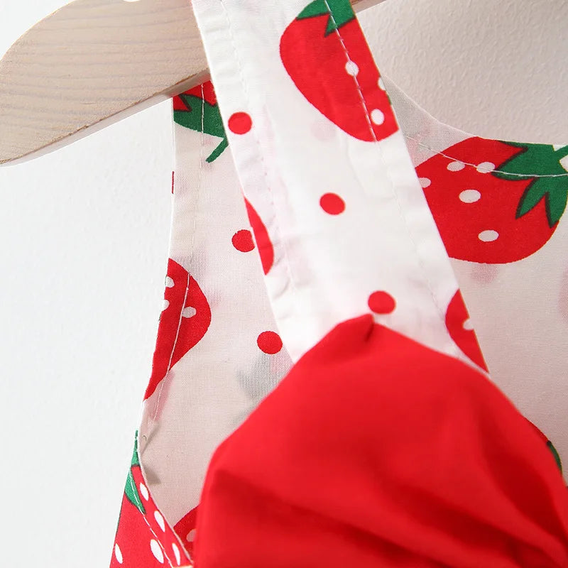 Nahaufnahme eines weißen Stoffes mit roter Erdbeer-Muster und einem weißen Riemchen, Teil eines Sommerkleid-Sets.