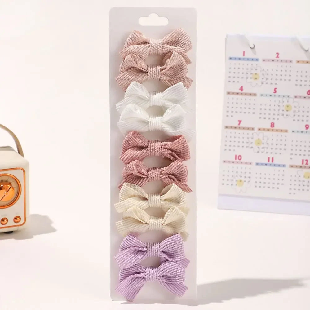 Présentation de diverses barrettes et pinces à cheveux en ruban de couleur pastel, arrangées verticalement sur une carte blan