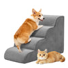 An orange and white dog is climbing a gray foam pet stairs ramp.