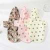 Three cartoon printed dog raincoats in brown, pink, and cream colors displayed on a white background.