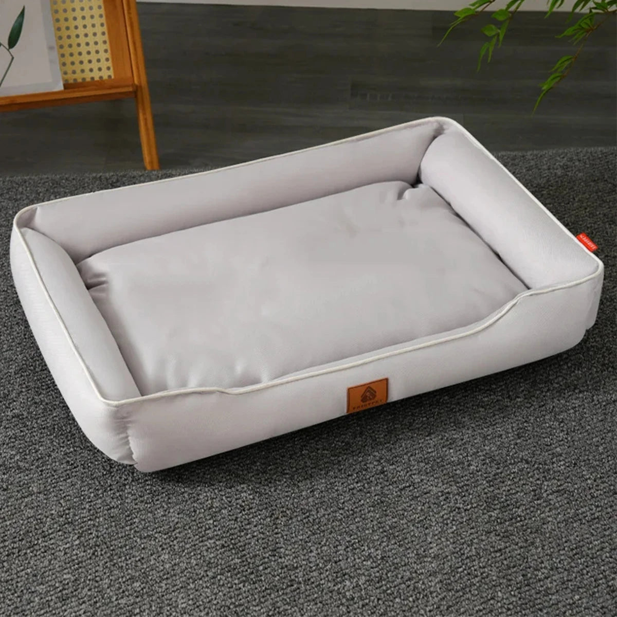 A white waterproof orthopedic dog bed with a removable cover lying on a gray carpet.