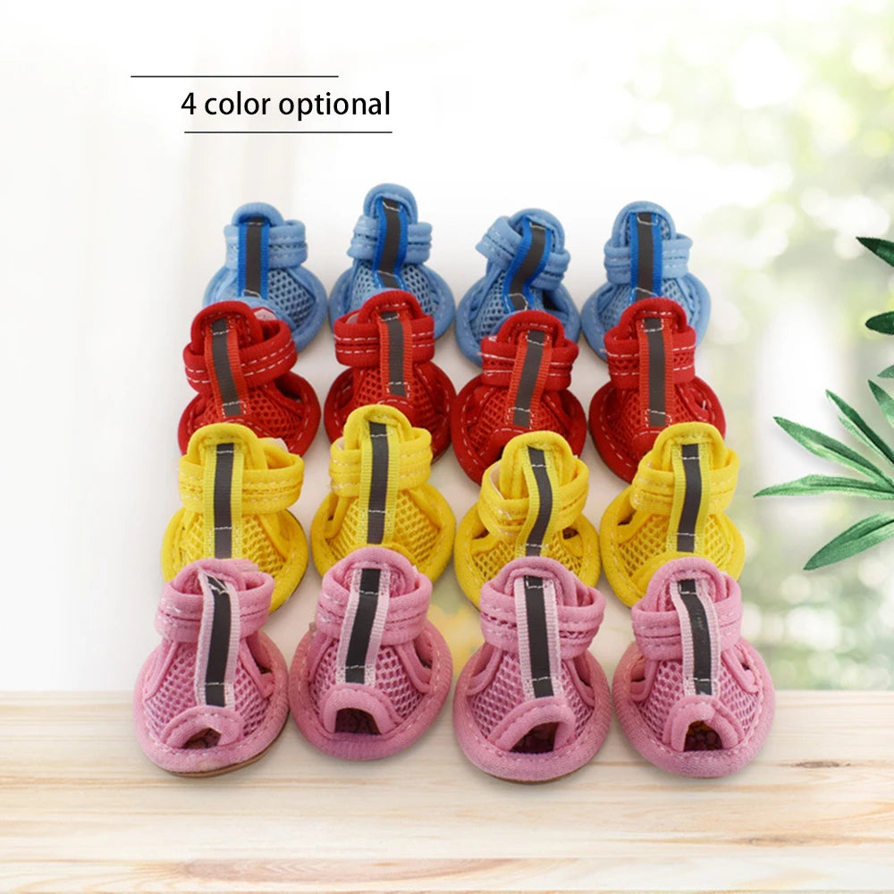 A set of four colorful summer walking shoes for dogs and cats displayed on a wooden surface.