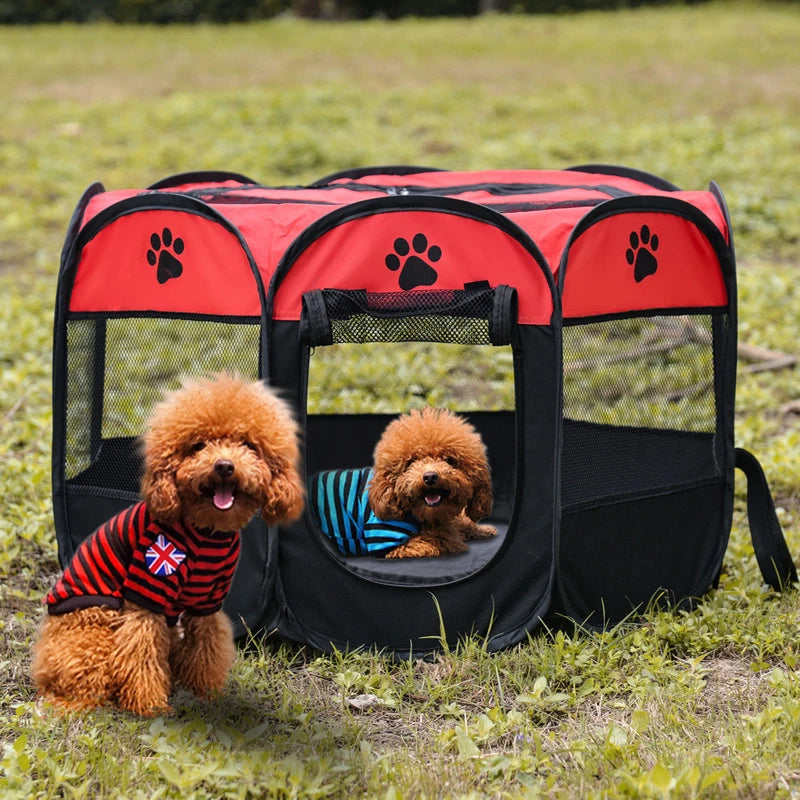 A small, fluffy dog is sitting inside a red and black folding octagonal pet cage outdoors.