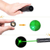 A hand holds a black laser pointer, demonstrating a green beam of light on a target.