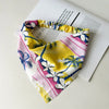 Diadema o pañuelo para el cabello con estampado floral amarillo y rosa, sobre una hoja de papel blanca.