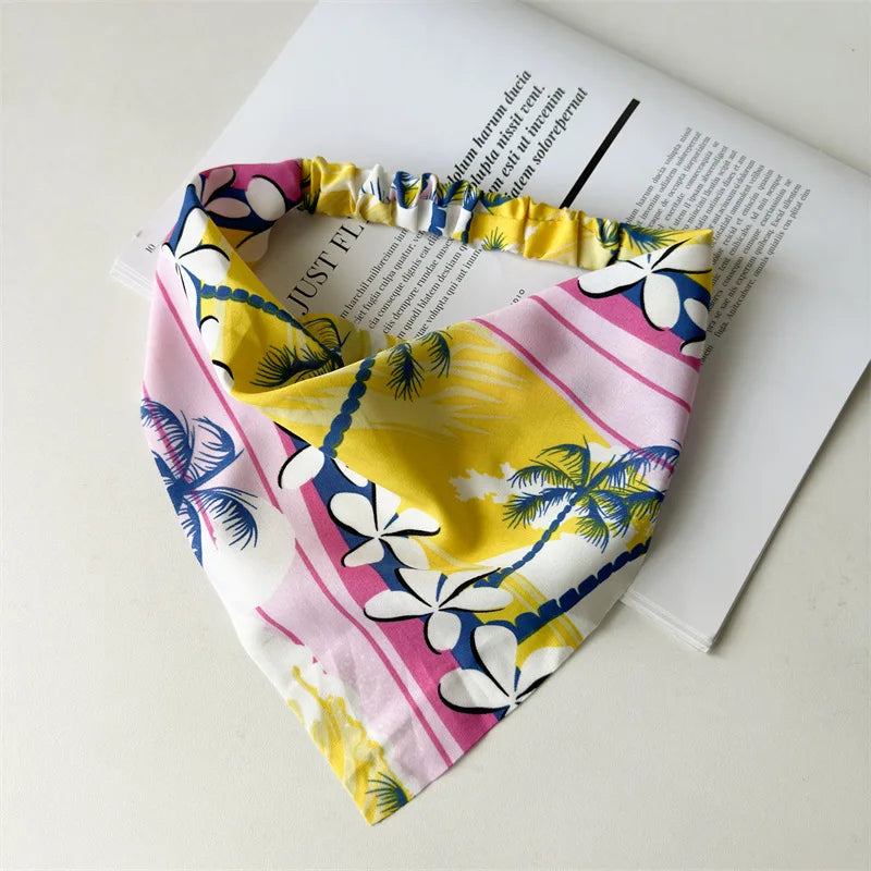 Diadema o pañuelo para el cabello con estampado floral amarillo y rosa, sobre una hoja de papel blanca.