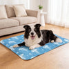 A black and white dog lying on a blue cooling gel pet mat indoors.