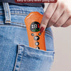 An orange paw-shaped ultrasonic dog repeller device is held by a hand against a denim background.