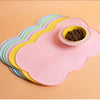 A stack of colorful silicone pet feeding mats, including a pink mat and a small bowl of dark pet food.