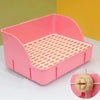 Una caja de arena rejillada rosa desmontable para pequeños mamíferos, mostrada sobre una superficie blanca.