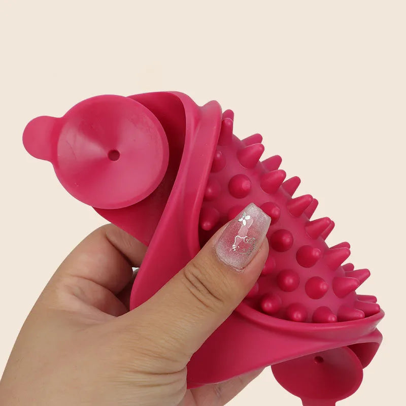 A hand holds a bright pink silicone licking mat for dogs and cats with suction cups.