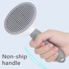 A hand holds a gray pet hair remover grooming brush with a non-ship handle.