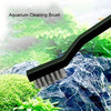 A black aquarium cleaning brush is shown against a background of green plants and rocks.