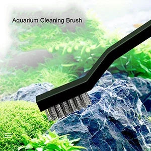 A black aquarium cleaning brush is shown against a background of green plants and rocks.