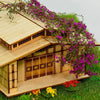 Holzminiaturhaus mit Rankwanddekoration aus lila Blumen und grünem Gras