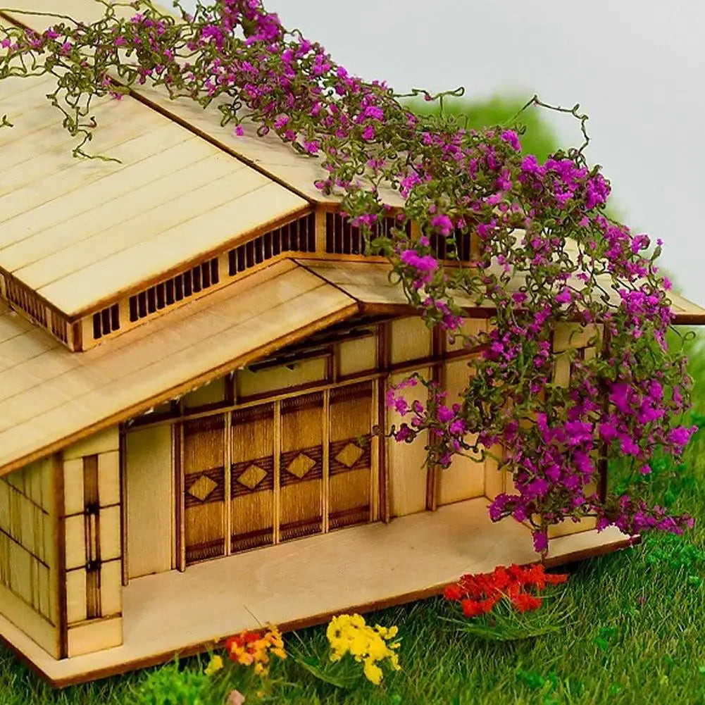 Holzminiaturhaus mit Rankwanddekoration aus lila Blumen und grünem Gras