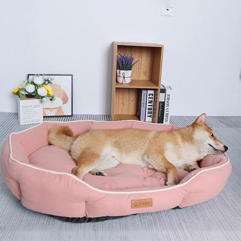 A light brown dog is lying on a pink corduroy pet sofa bed in front of a wooden shelf.