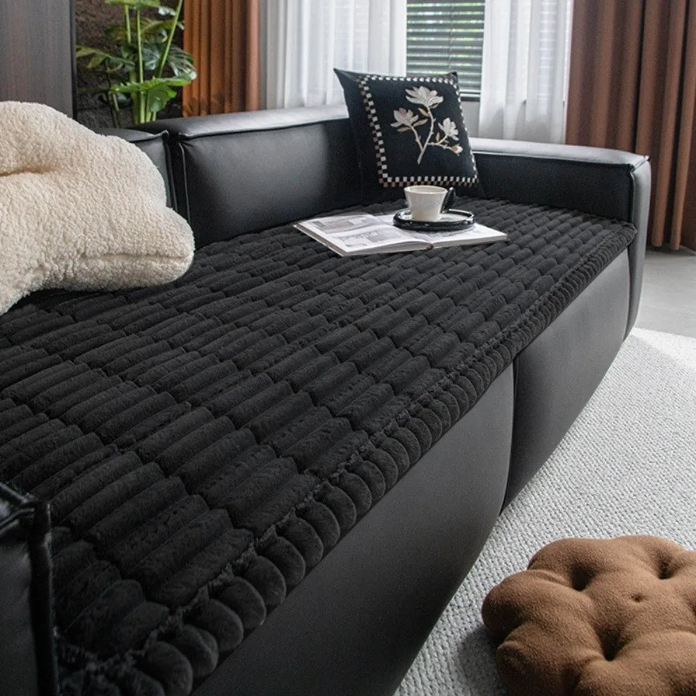 A black plaid flannel pet seat protector and car mat placed on a dark leather sofa.