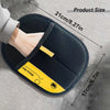 A hand is holding a black silicone pet hair removal glove with yellow accents on a gray fabric background.