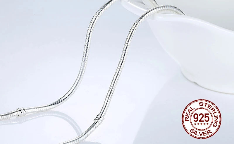 A silver snake chain necklace with a heart charm displayed on a white background.