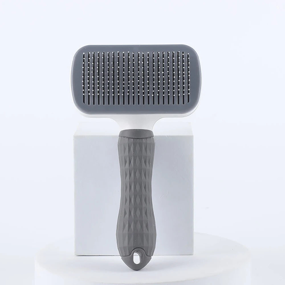 A gray pet hair removal brush with massage pins is displayed on a white stand.