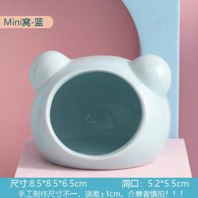 White ceramic hamster house with a round opening displayed against a pink background.