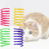 Eine Katze interagiert mit mehreren farbigen Spiralspielzeugen: rosa, gelb, grün und lila.