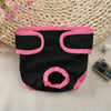 A black reusable dog diaper with pink trim is displayed on a woven mat.