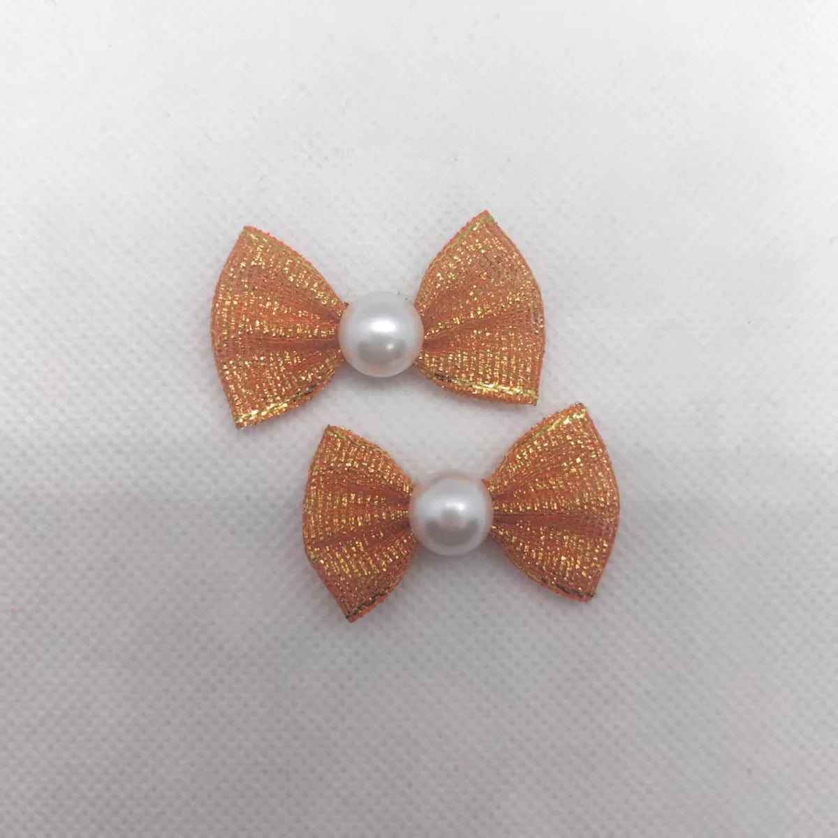 Ein Set aus drei golden-orangen Welpe-Bowknoten mit Perlen-Zentren für das Haustierpflege.