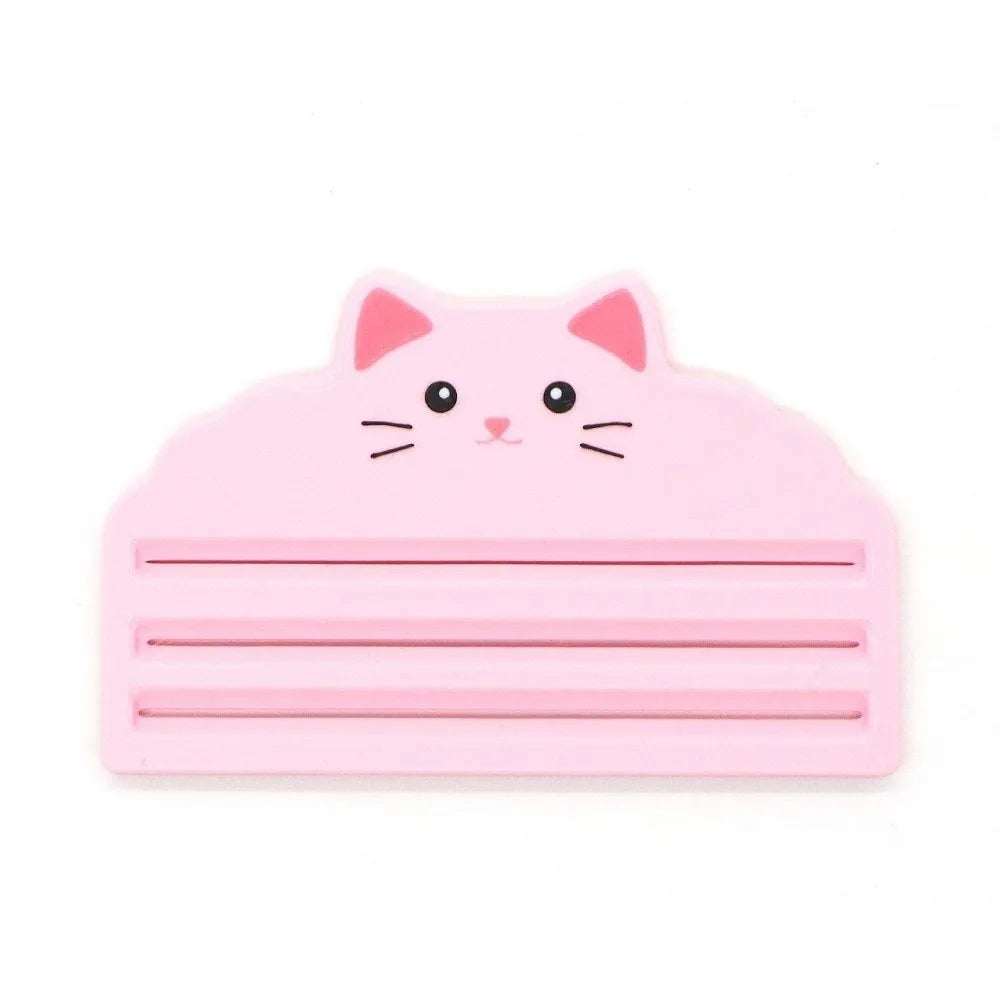 A pink reusable cat food pouch scraper shaped like a cat's face.