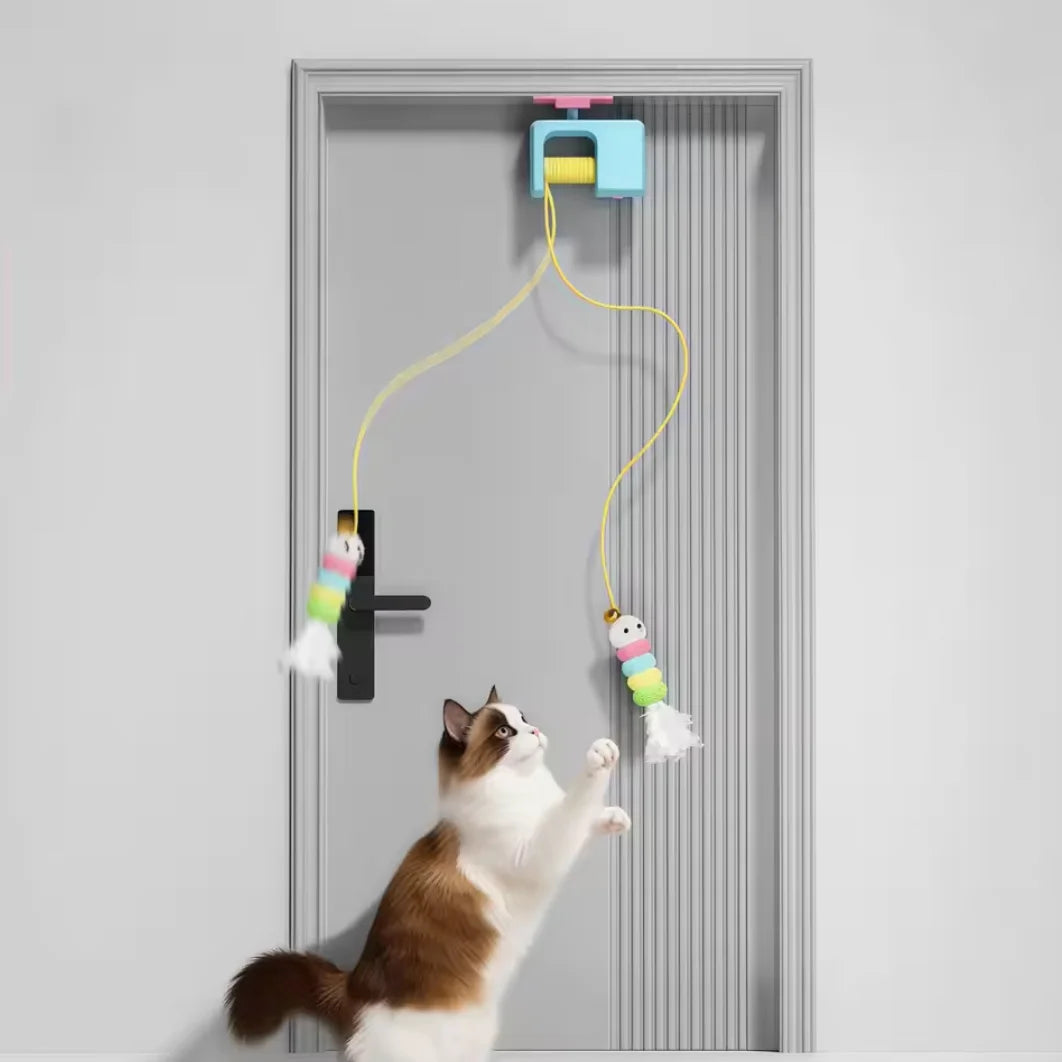 Eine Katze spielt mit einem automatischen elektrischen Spielzeug, das an einer Tür befestigt ist.