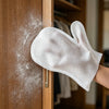 Guante desechable blanco para quitar pelo de mascotas, usado para retirar pelusa de una puerta de armario de madera.