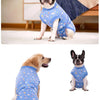 A black and white dog wearing a blue patterned recovery suit for post-surgery protection.