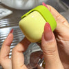 A hand holds a lime green portable lint roller for pet hair removal against a blurred background.