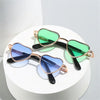 Pair of heart-shaped pet sunglasses with green and blue lenses displayed on a white stand.