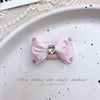 Pink bow hair accessory with rhinestone pearl accents displayed on a white plate.