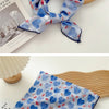 Écharpes en coton à motifs floraux bleus et blancs nouées en nœud, posées sur une surface en bois.