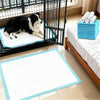 Black and white dog resting on a blue training pad inside a black pet cage.