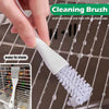 Une main tient une brosse de nettoyage blanche à poils, positionnée sur une grille de cage pour animaux en fil de fer.