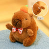 A brown capybara plush doll with an orange-green hood and wings sitting on a blue surface.