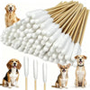 A bundle of long white cotton swabs with small white balls for pet ear cleaning next to several dogs.
