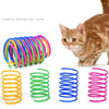 A collection of colorful spiral spring cat toys, including yellow, green, blue, and pink, next to an orange tabby cat.